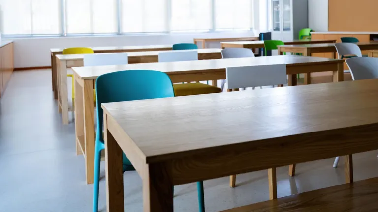Wooden tables and colourful chairs in an empty, sunlit classroom